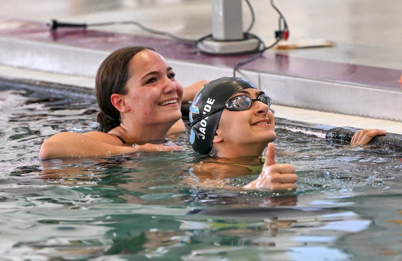 Cape senior Sidney Caldwell, left, and junior Mia Jaoude celebrate their second- and first-place finishes in the 50 freestyle with their parents in the grandstands.
