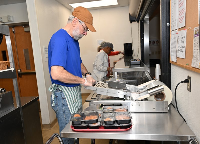 Volunteer John King seals the dinners to be distributed with Meals on Wheels.