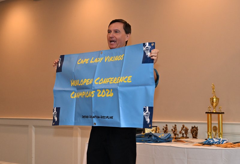 Cape coach Ron Dukes displays the banner presented to all seniors on the squad.