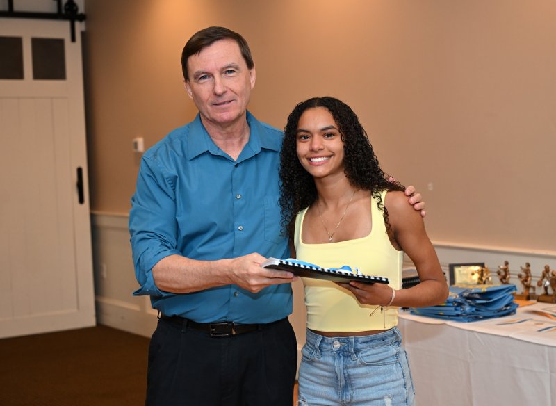 Sophomore Laura Karen Lima receives a varsity book from coach Ron Dukes.