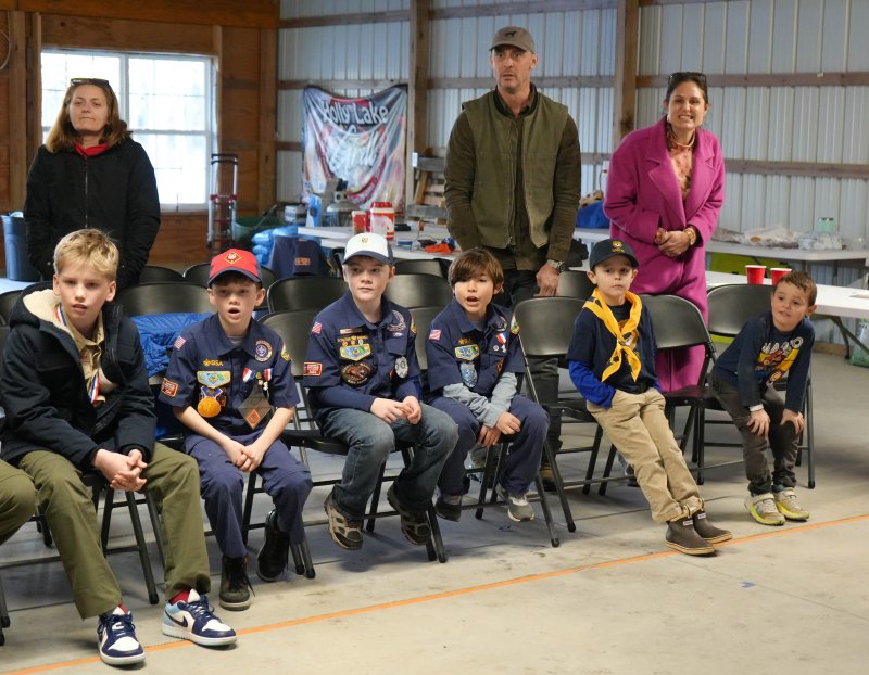 Watching a close race in back are (l-r) Pack 1 New Member Coordinator Diana Huebler and the Kenton family. Sitting in front are scouts Beau Berard, Julien Berard, James Huebler, Lucas Mesiti and Pierce Kenton.