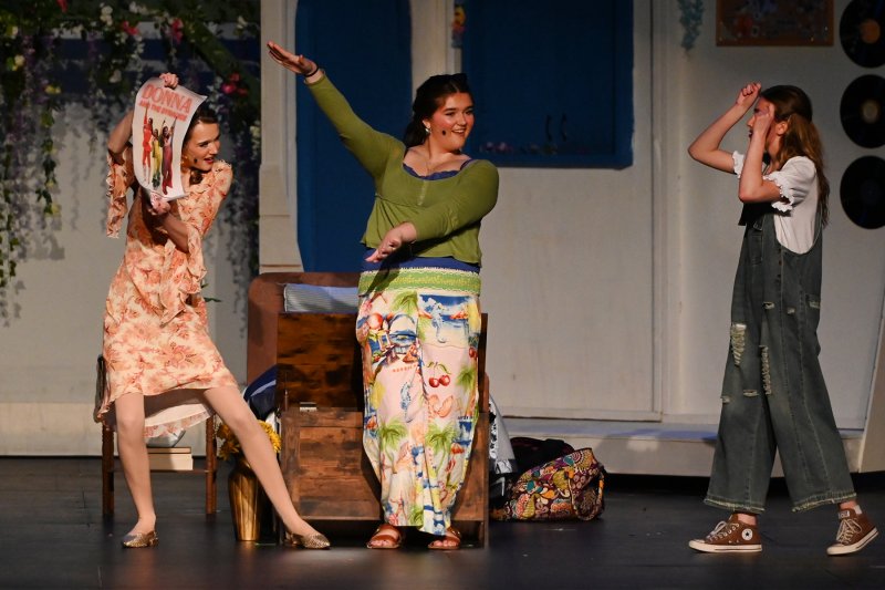 Donna, played by Daphne Mock, right, is shown an old photograph of herself with her friends Tanya, played by Ruby Manos, and Rosie, played by Anna Currence.