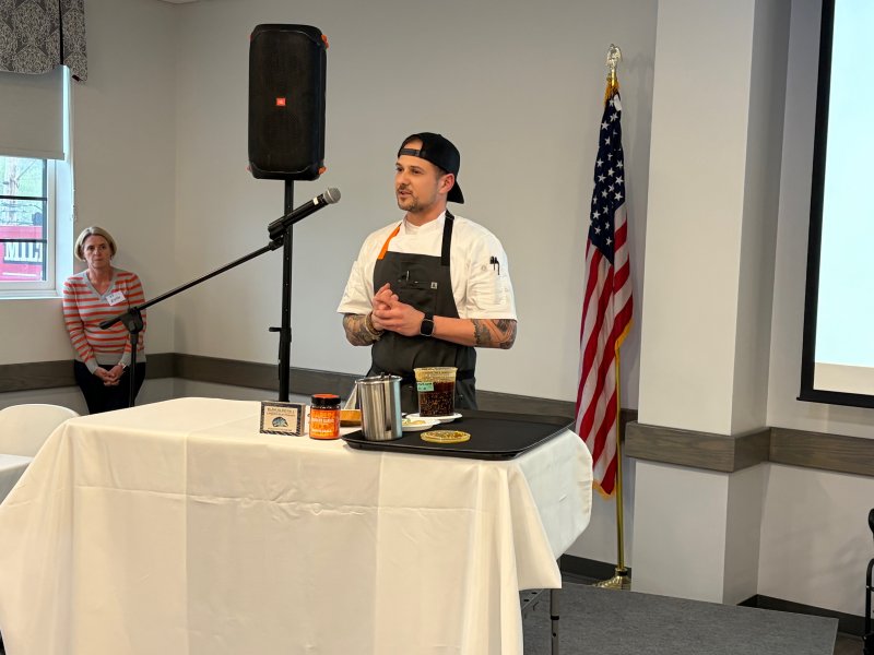 Chef David Kneller explains how he made the evening’s first course: white bean hummus with smoked mussels topped with chili garlic crunch and pickled red onions.